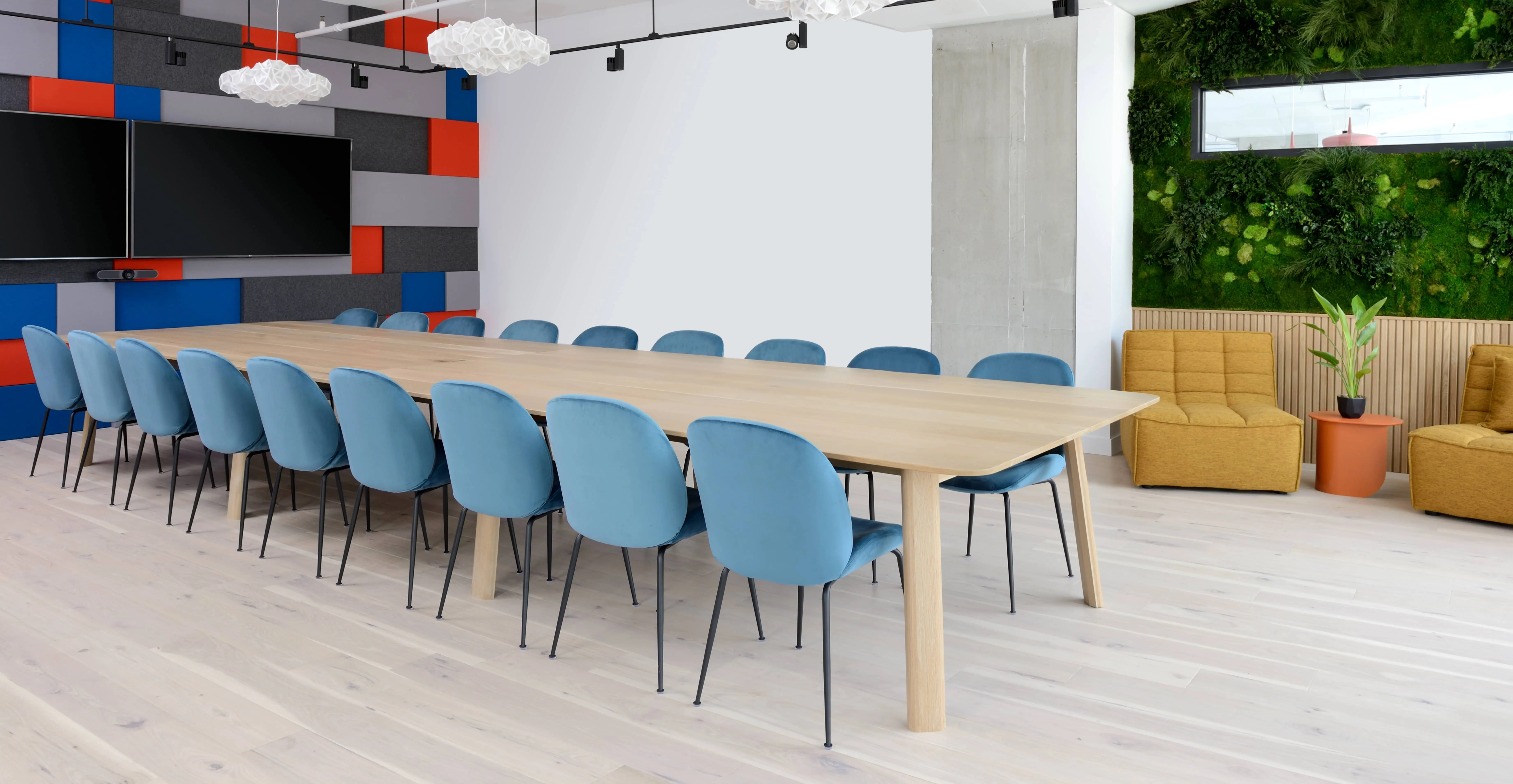 A wooden conference room table with blue chairs around it